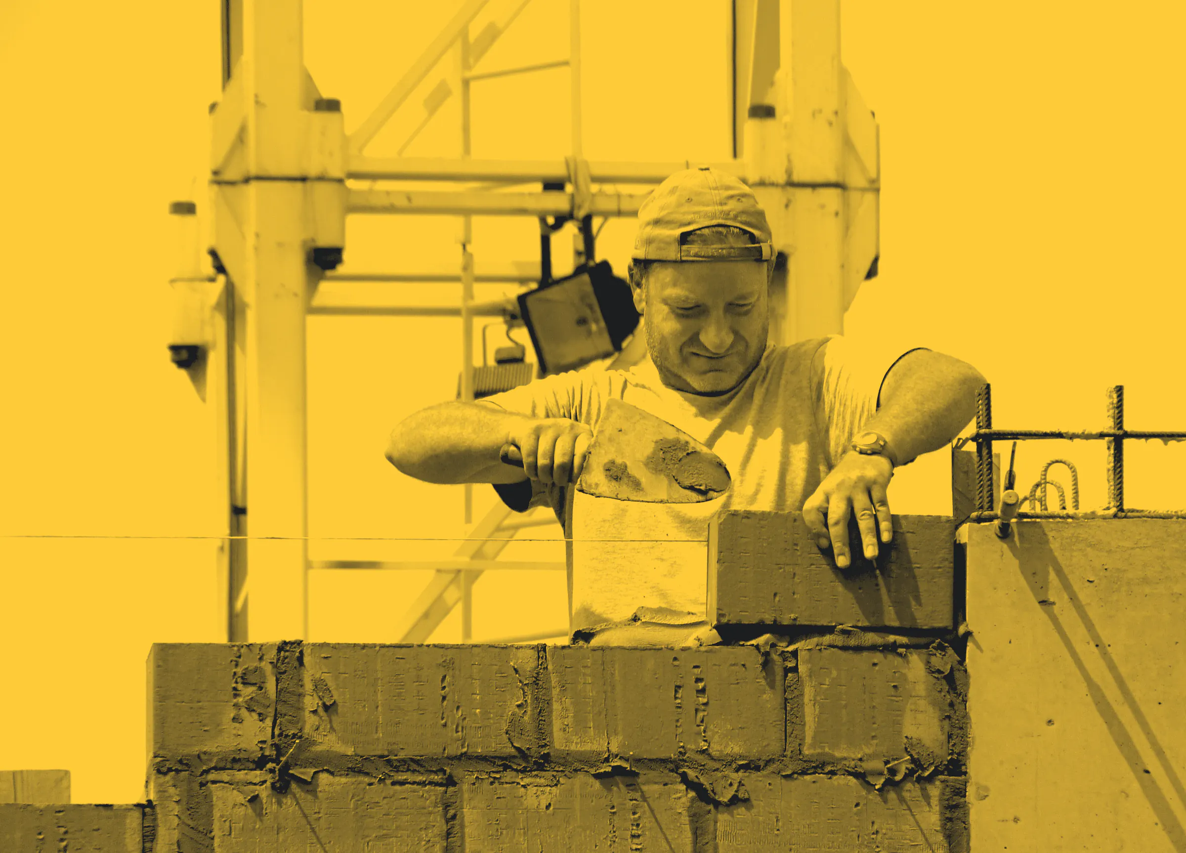A bricklayer spreading mortar along a new course of bricks